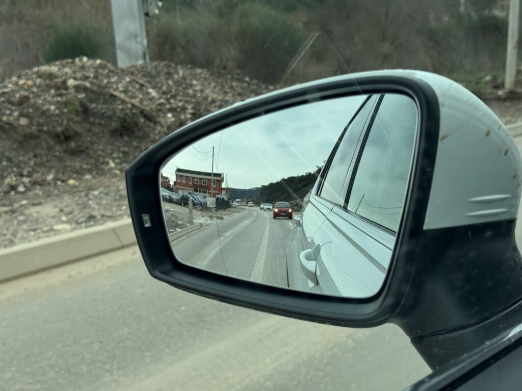 Road construction near Lastva Grbaljska — gravel road and construction seen in side mirror