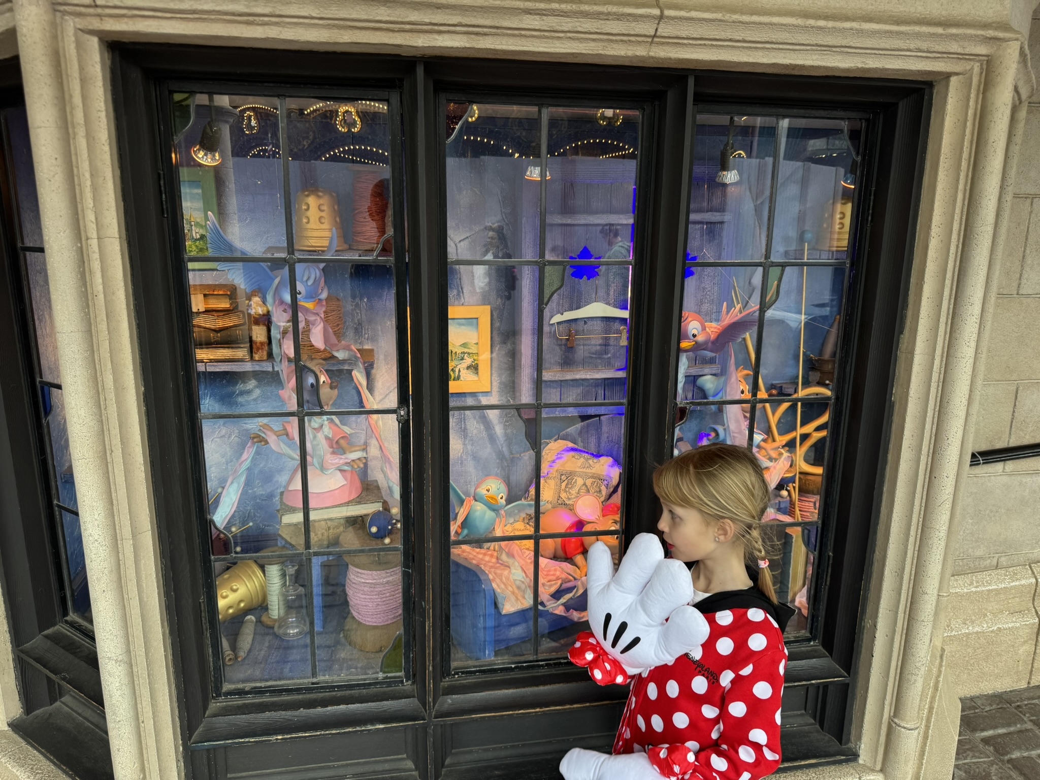 Child in Minnie ears looking into a Disneyland Paris display window
