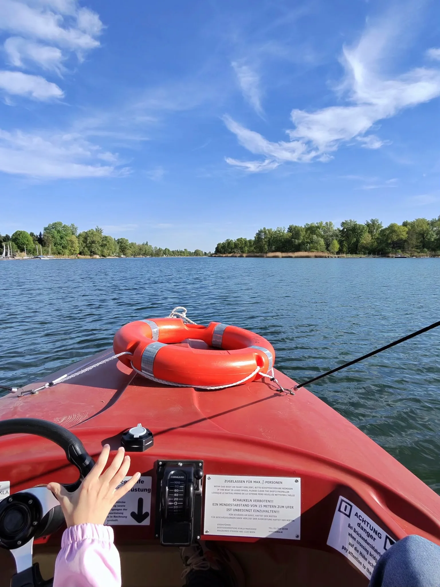Forward view from an electric boat on Alte Donau with a child’s hand near the controls.