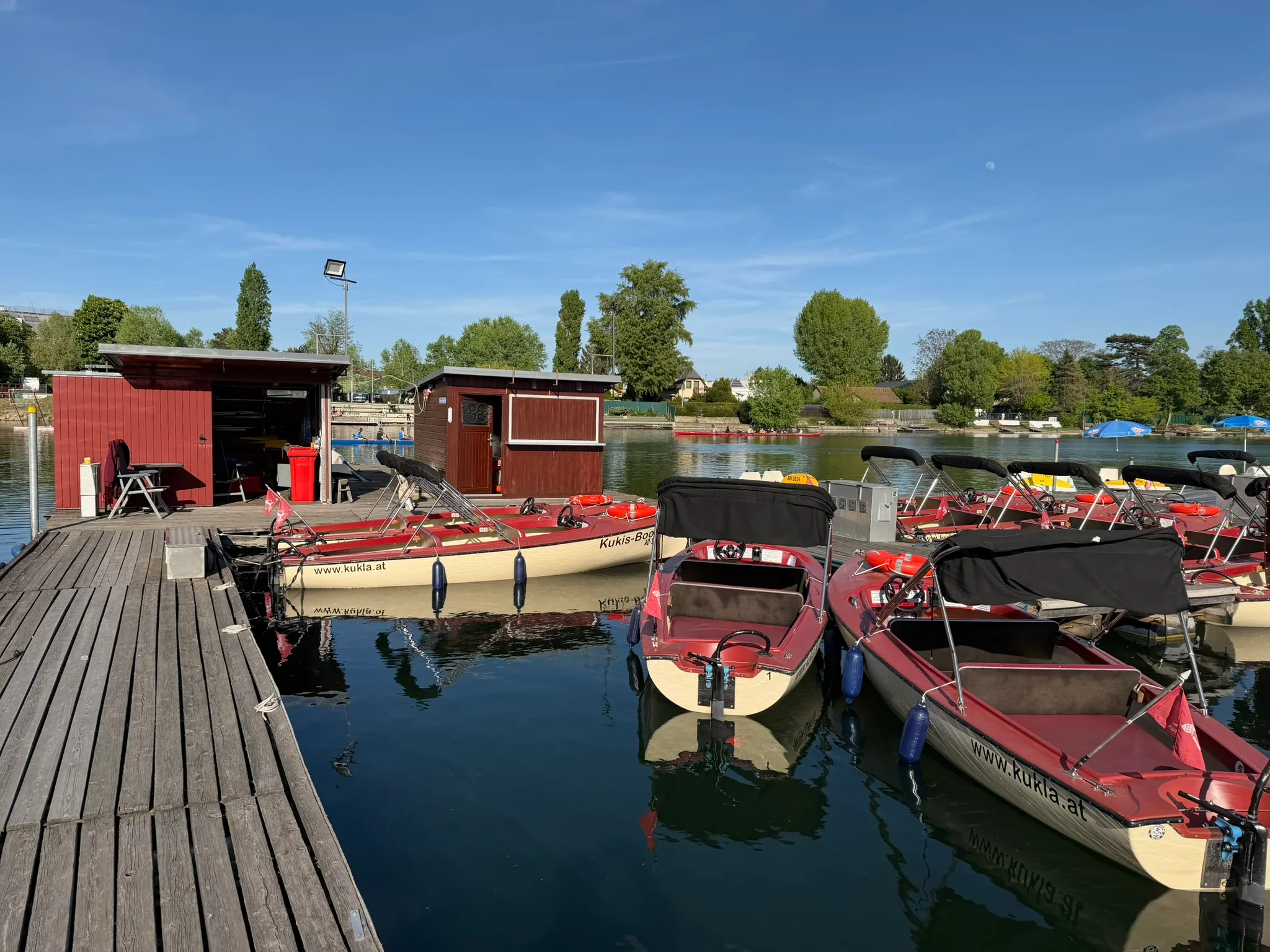 Red electric rental boats docked at the Alte Donau marina in Vienna.