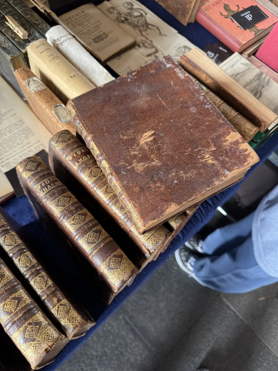 Antique book stall in Milan with centuries-old books stacked in piles